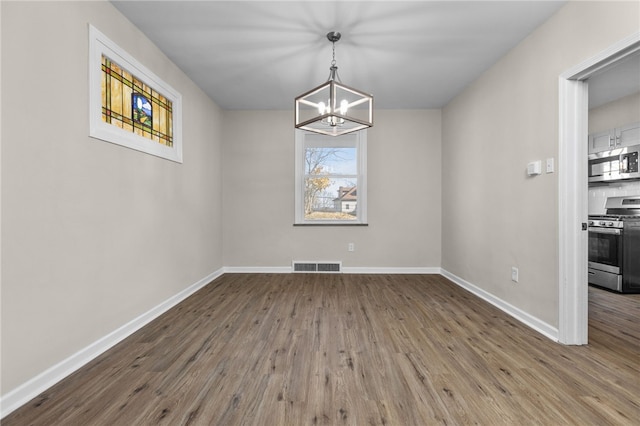 unfurnished room featuring a chandelier and hardwood / wood-style flooring