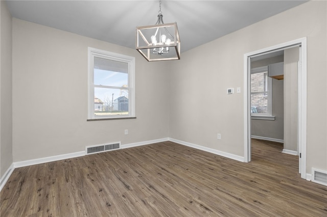 empty room featuring a chandelier and dark hardwood / wood-style flooring