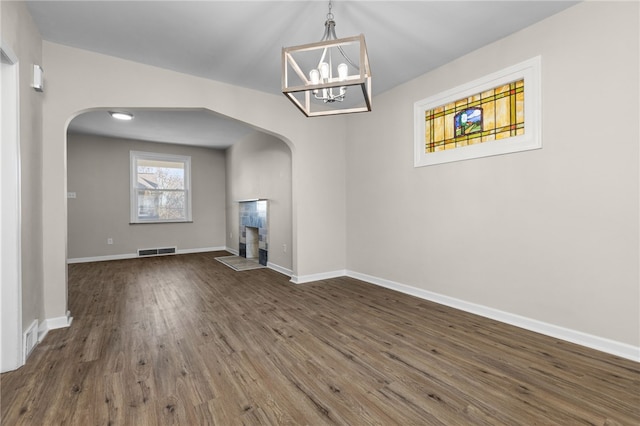 unfurnished living room featuring an inviting chandelier and dark hardwood / wood-style flooring