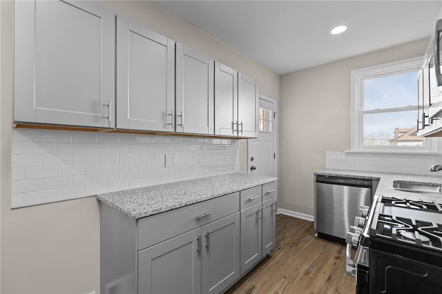 kitchen with tasteful backsplash, hardwood / wood-style floors, appliances with stainless steel finishes, gray cabinetry, and sink