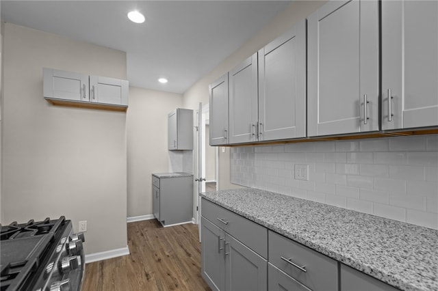 kitchen featuring backsplash, gray cabinets, dark hardwood / wood-style floors, and light stone counters