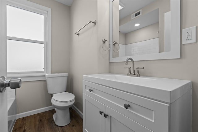 bathroom with wood-type flooring, toilet, vanity, and a wealth of natural light