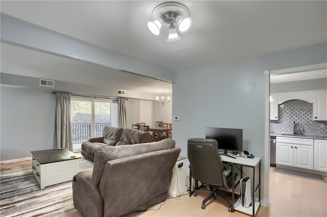 living room featuring a notable chandelier, sink, and light wood-type flooring