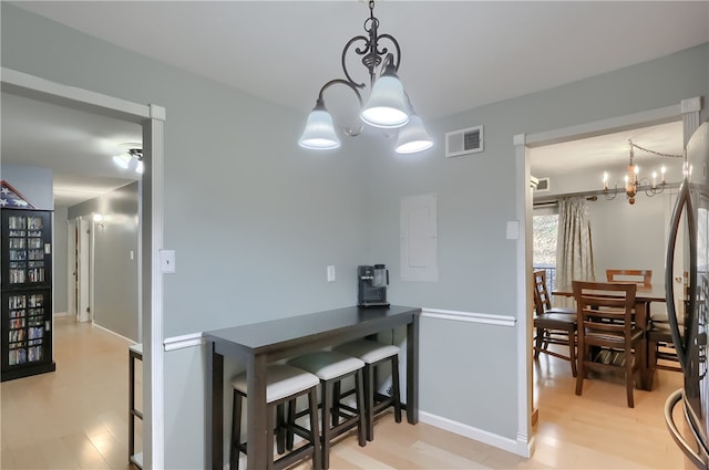 interior space with decorative light fixtures, a chandelier, black fridge, and light wood-type flooring