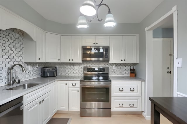 kitchen featuring sink, stainless steel appliances, white cabinets, a chandelier, and tasteful backsplash