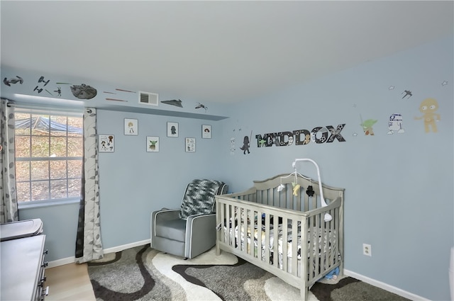 bedroom with a nursery area and light hardwood / wood-style flooring