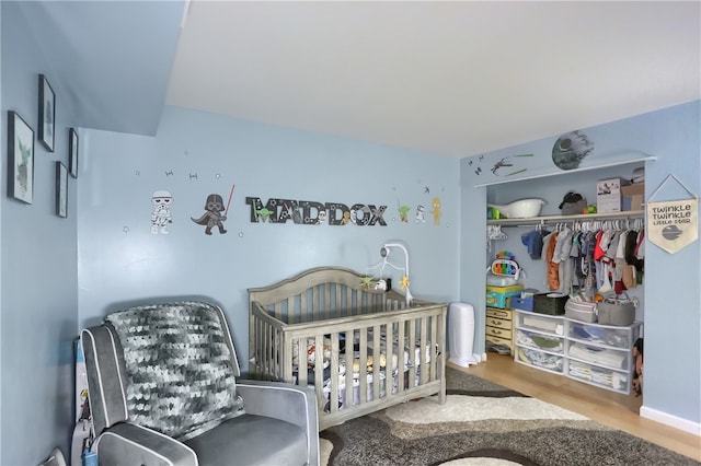 bedroom with a closet, a nursery area, and light wood-type flooring