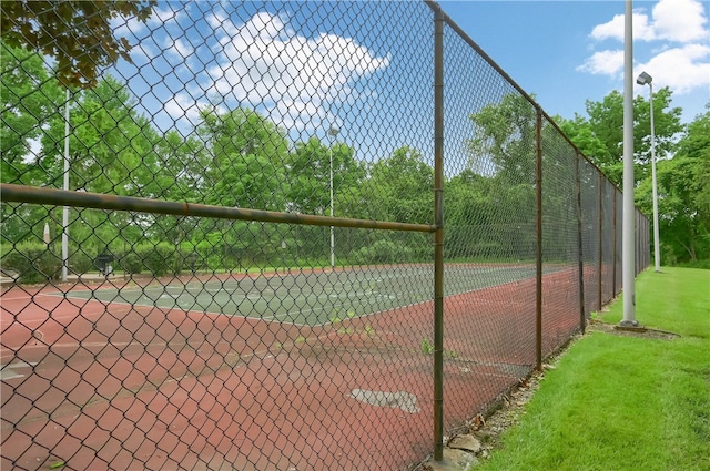 view of tennis court featuring a lawn