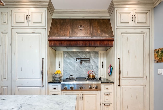 kitchen with dark stone counters, backsplash, cream cabinetry, and stainless steel gas cooktop