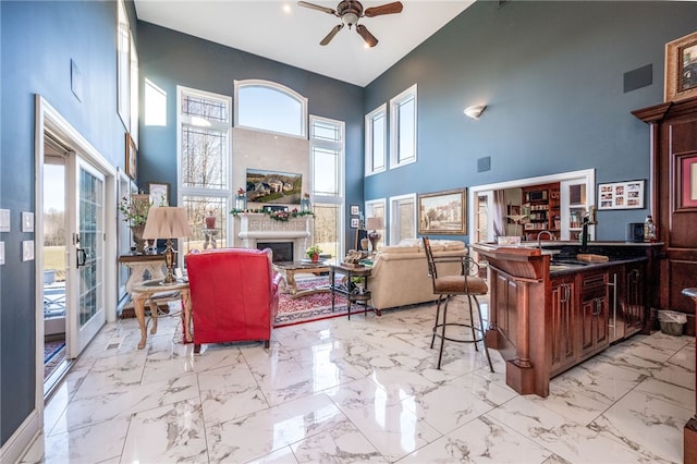 kitchen with a kitchen bar, light tile flooring, ceiling fan, and a high ceiling