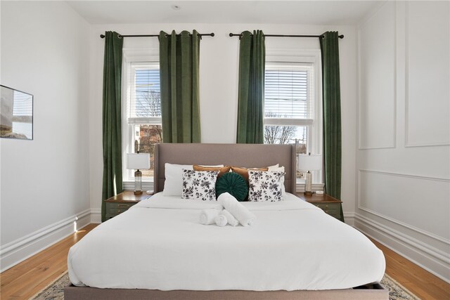 bedroom with multiple windows and hardwood / wood-style flooring