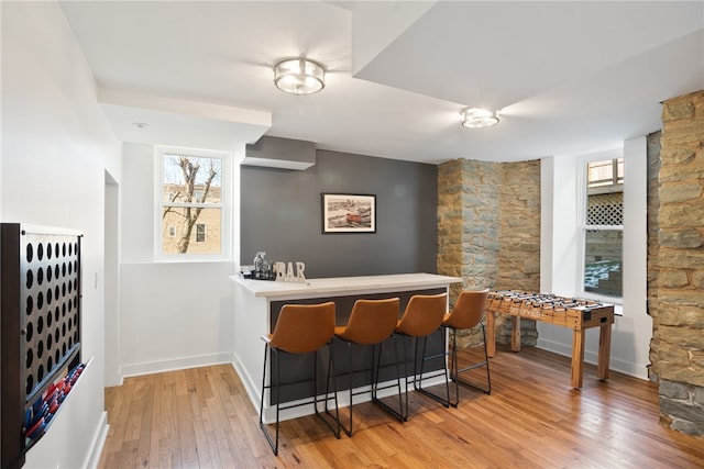 kitchen featuring light hardwood / wood-style flooring, kitchen peninsula, and a kitchen bar