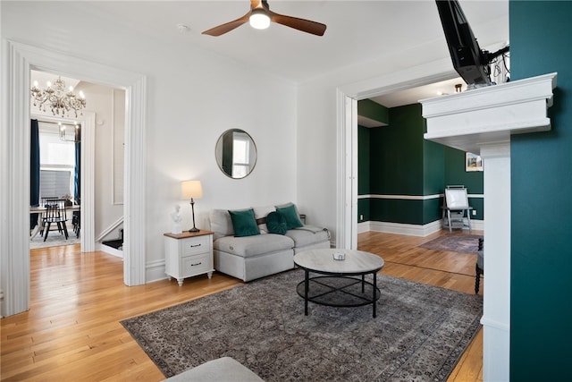 living room with ceiling fan with notable chandelier and light hardwood / wood-style floors