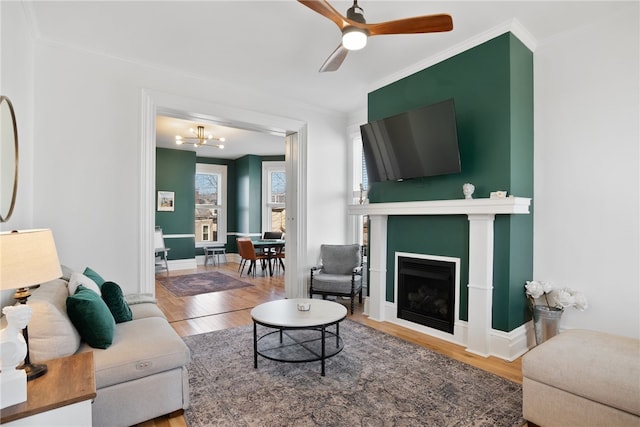 living room featuring ceiling fan with notable chandelier, hardwood / wood-style flooring, and ornamental molding