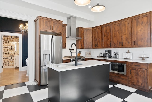 kitchen featuring wall chimney exhaust hood, dark tile flooring, tasteful backsplash, stainless steel appliances, and a center island with sink