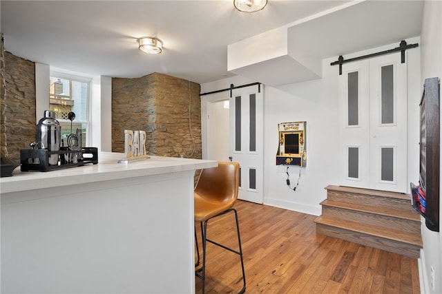 kitchen with kitchen peninsula, a barn door, light hardwood / wood-style flooring, and a breakfast bar