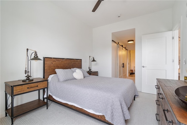 bedroom with light carpet, a barn door, connected bathroom, and ceiling fan