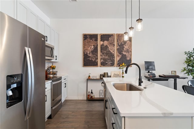 kitchen with a kitchen island with sink, sink, hanging light fixtures, dark hardwood / wood-style flooring, and appliances with stainless steel finishes