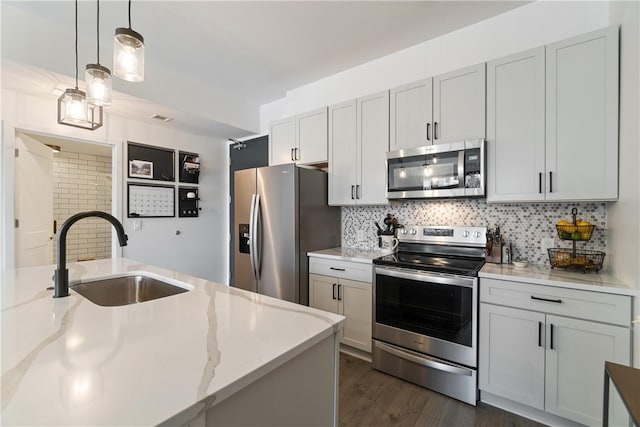 kitchen featuring tasteful backsplash, stainless steel appliances, decorative light fixtures, sink, and dark hardwood / wood-style floors