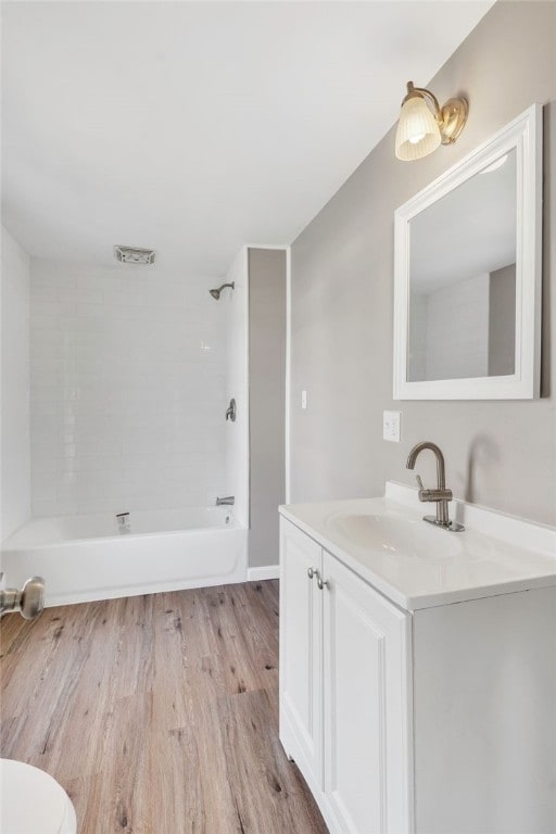 full bathroom featuring vanity, wood-type flooring, toilet, and tiled shower / bath