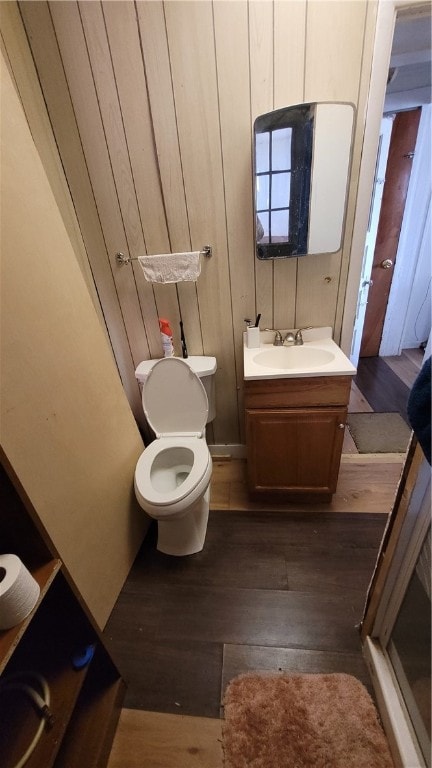 bathroom with vanity, wooden walls, hardwood / wood-style floors, and toilet