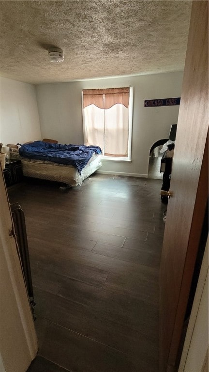 bedroom with dark hardwood / wood-style flooring and a textured ceiling