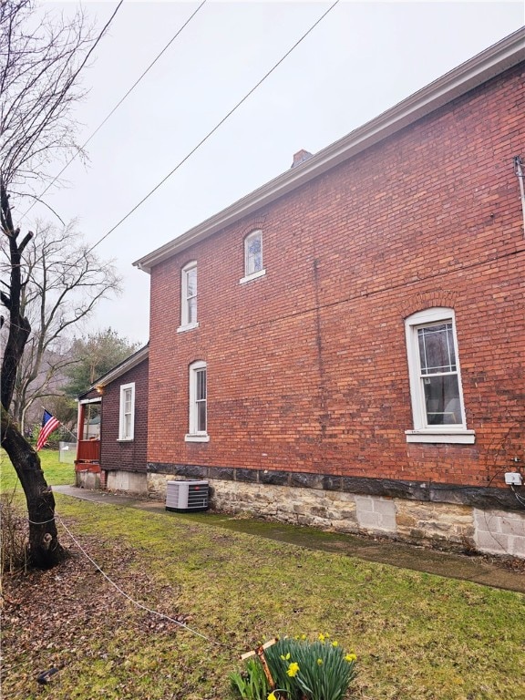 view of side of property with a lawn and central air condition unit