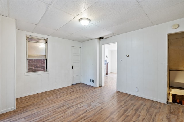 spare room with a paneled ceiling and wood-type flooring