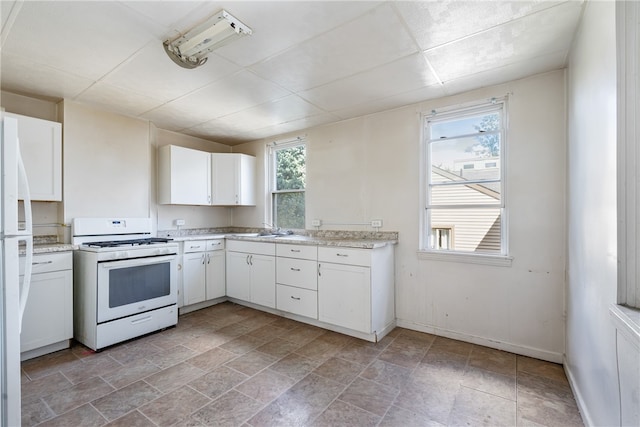 kitchen with white range with gas cooktop, sink, and white cabinets