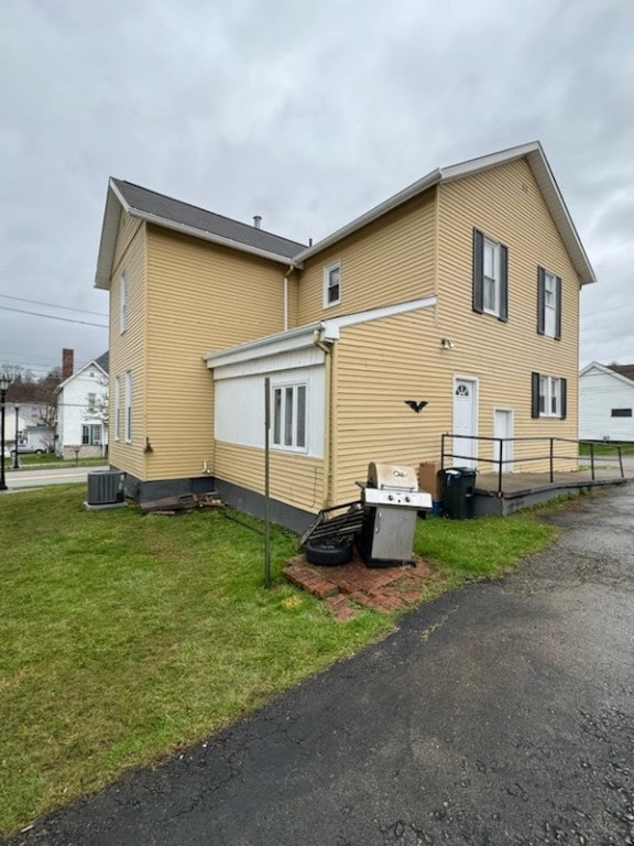 rear view of house with central air condition unit and a yard