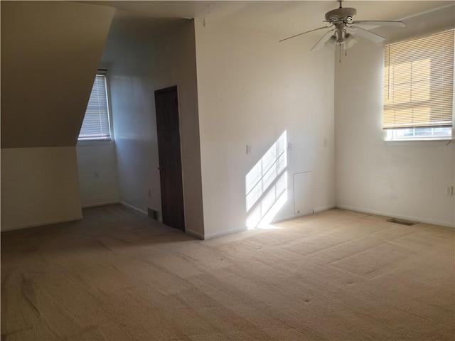 spare room featuring ceiling fan, light colored carpet, and lofted ceiling