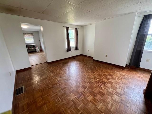 spare room featuring parquet flooring and a paneled ceiling