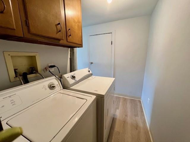 clothes washing area with cabinets, light hardwood / wood-style floors, and washer and clothes dryer