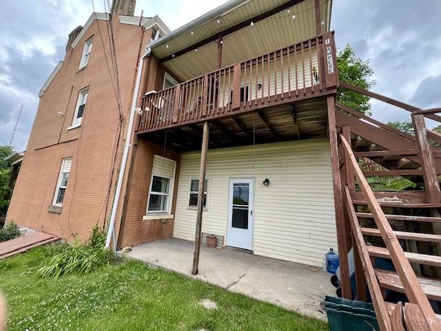 rear view of property featuring a wooden deck and a patio