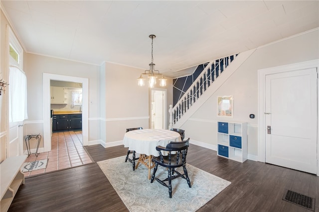 dining room with dark tile flooring, an inviting chandelier, and ornamental molding