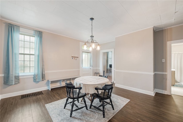 dining area featuring a notable chandelier, dark hardwood / wood-style floors, and ornamental molding