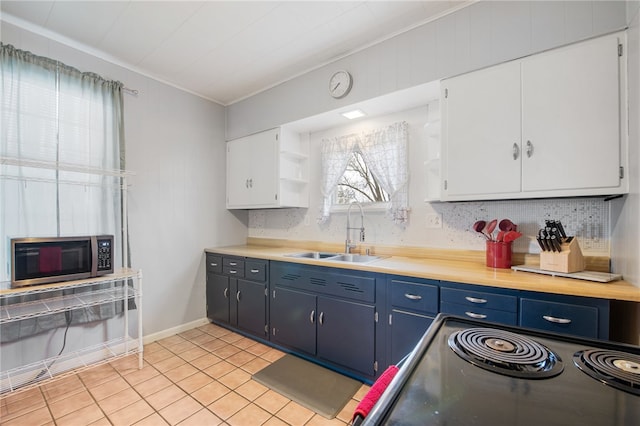 kitchen featuring white cabinets, stove, light tile floors, blue cabinets, and sink