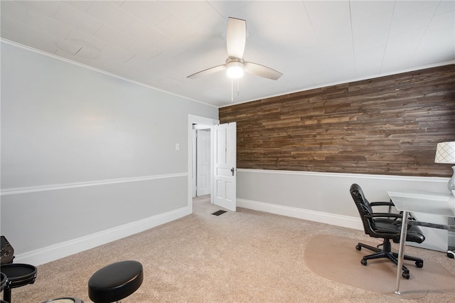 carpeted home office with wood walls and ceiling fan