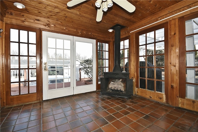 unfurnished sunroom with wood ceiling, ceiling fan, and a wood stove