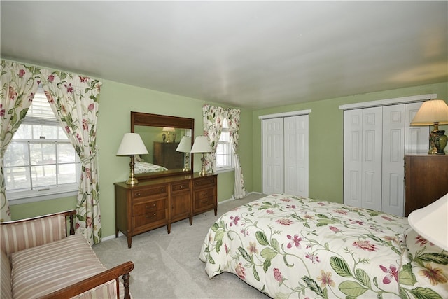 bedroom with light carpet, multiple closets, and multiple windows