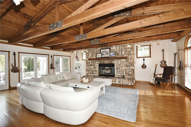 living room featuring hardwood / wood-style floors, a stone fireplace, beamed ceiling, and wood ceiling