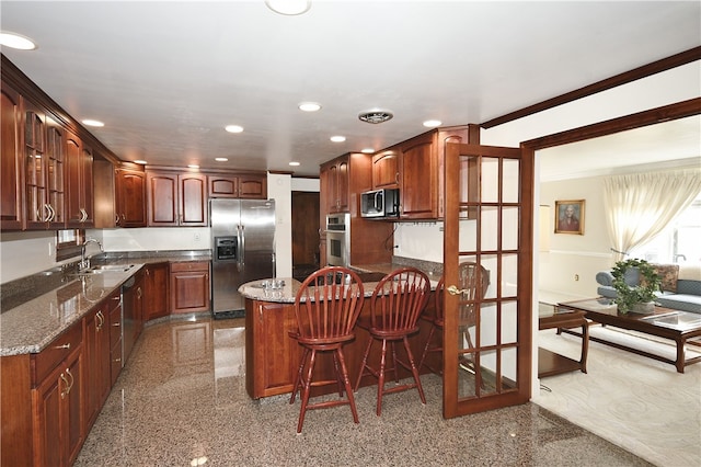 kitchen featuring a breakfast bar area, sink, appliances with stainless steel finishes, and dark stone counters