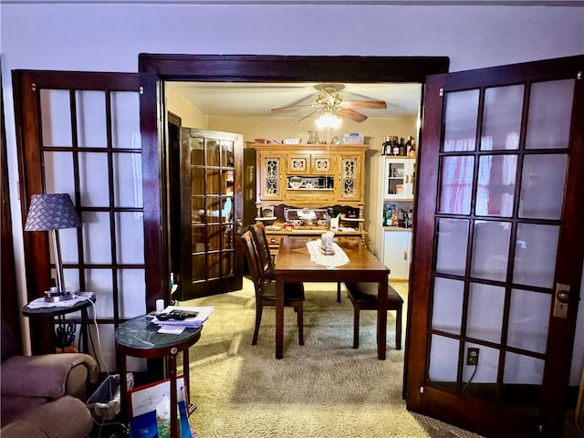 carpeted dining area with ceiling fan and french doors