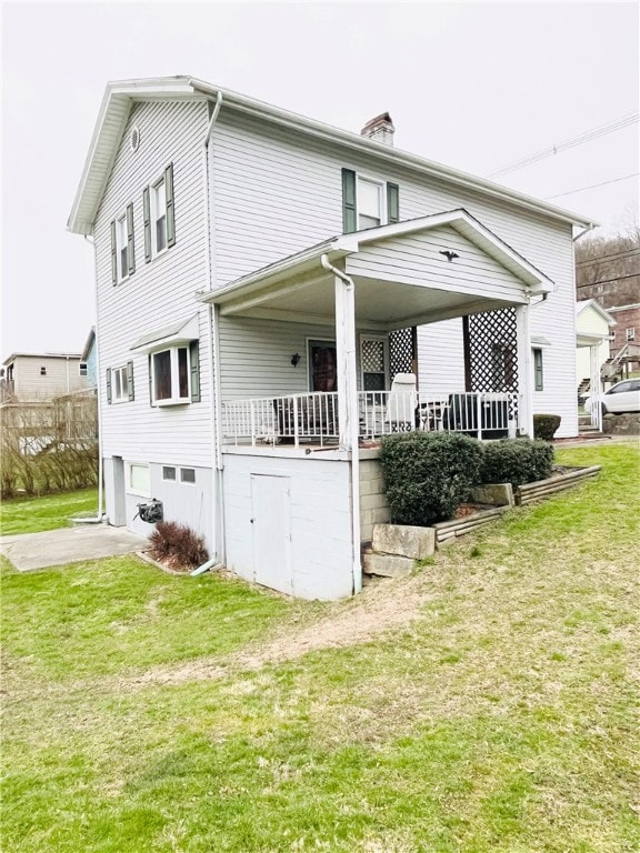 back of house with a yard, covered porch, and a garage