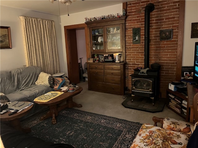 carpeted living room featuring brick wall, ceiling fan, and a wood stove