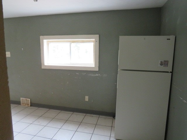 interior space featuring light tile flooring and white fridge