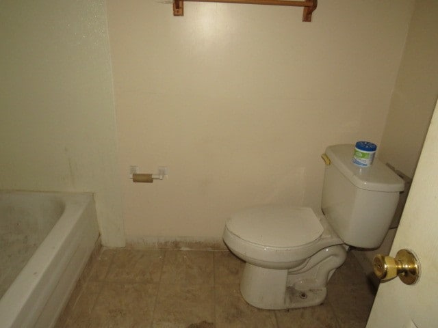 bathroom featuring tile flooring, toilet, and a bathtub