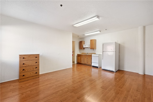 unfurnished living room with light hardwood / wood-style floors, a textured ceiling, and sink