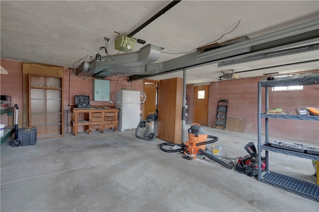 garage featuring a workshop area, white fridge, and a garage door opener