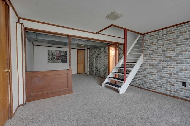 basement featuring carpet floors, crown molding, and brick wall